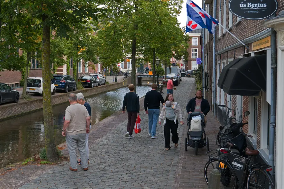 Mensen lopen langs een gracht in de binnenstad van Leiden